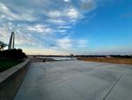 An empty concrete platform above the Mississippi River, the St. Louis Arch is on the left, the river on the right.