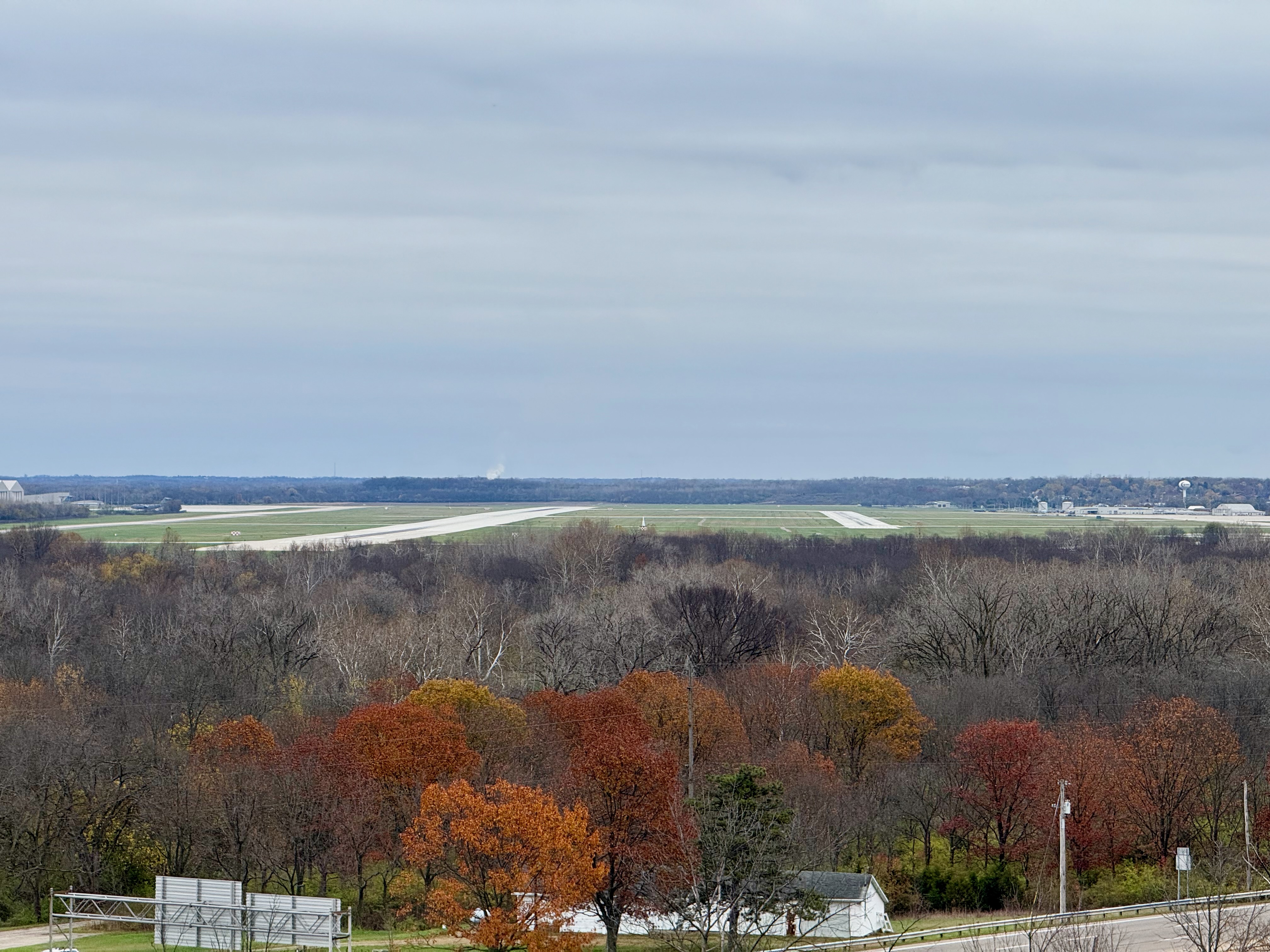 The runways of Wright-Patterson Air Force Base in the distance. The lower portion of the photo shows a bunch of trees, some of them still with late-fall colors.